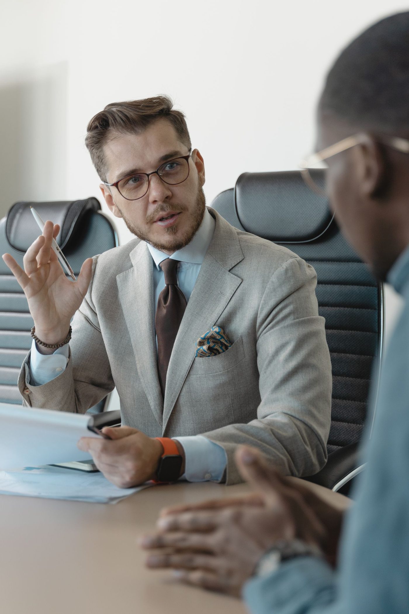 Two professionals talking across a desk in a bright office