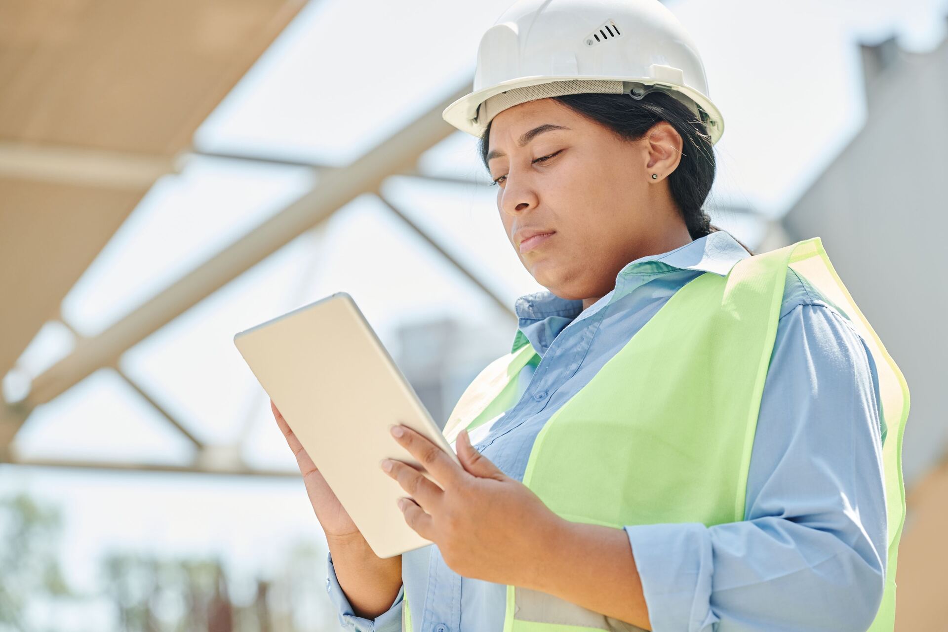Field technician in a hard hat reviewing a tablet on a job site